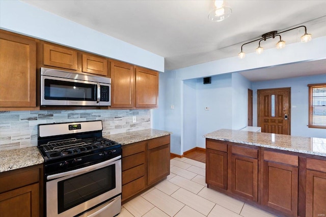 kitchen featuring stainless steel appliances, light stone countertops, and decorative backsplash