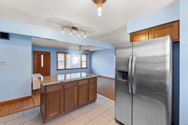 kitchen with light stone counters, stainless steel fridge, a center island, and track lighting