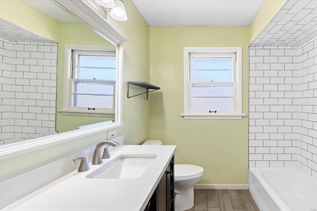 full bathroom featuring hardwood / wood-style flooring, vanity, tiled shower / bath combo, and toilet