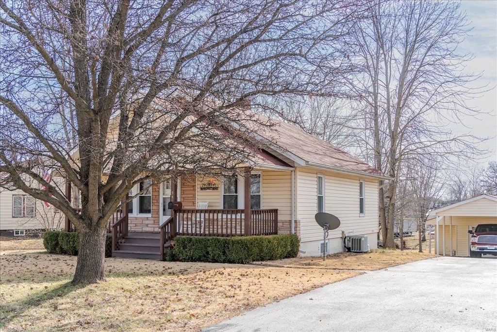 view of front facade featuring central AC, a carport, and covered porch