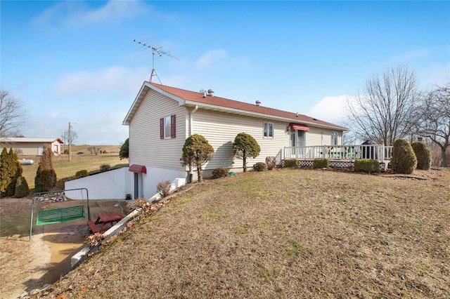 rear view of property featuring a wooden deck and a lawn