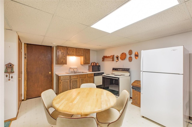 kitchen featuring a drop ceiling, sink, and white appliances