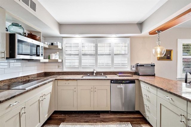 kitchen featuring sink, appliances with stainless steel finishes, dark hardwood / wood-style floors, decorative light fixtures, and dark stone counters