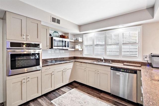 kitchen with stainless steel appliances, sink, stone counters, and dark hardwood / wood-style floors