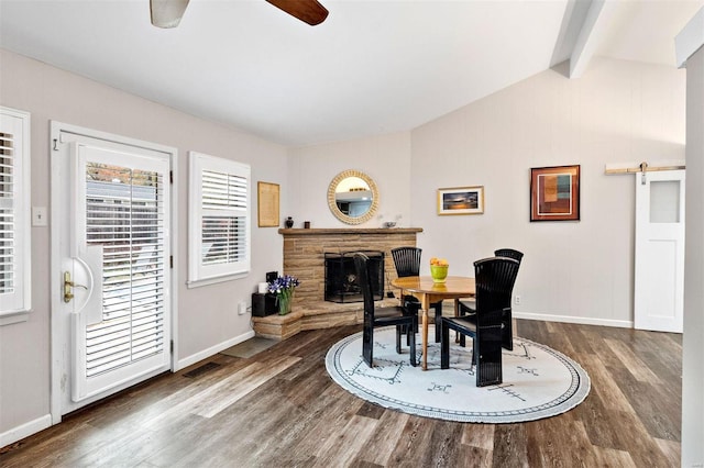 dining space with wood-type flooring, a barn door, vaulted ceiling with beams, and ceiling fan