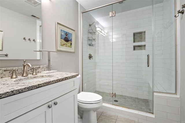 bathroom featuring tile patterned flooring, vanity, a shower with door, and toilet