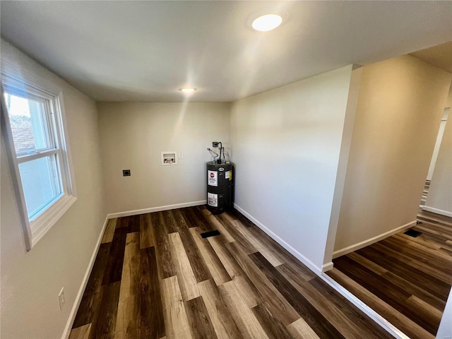 unfurnished room featuring dark wood-type flooring and water heater