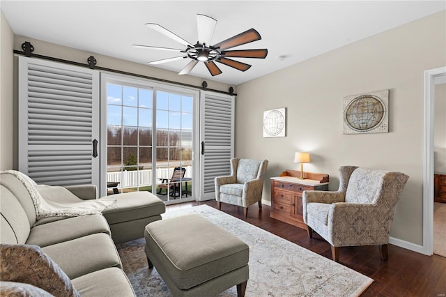 living room with dark hardwood / wood-style flooring, a barn door, and ceiling fan