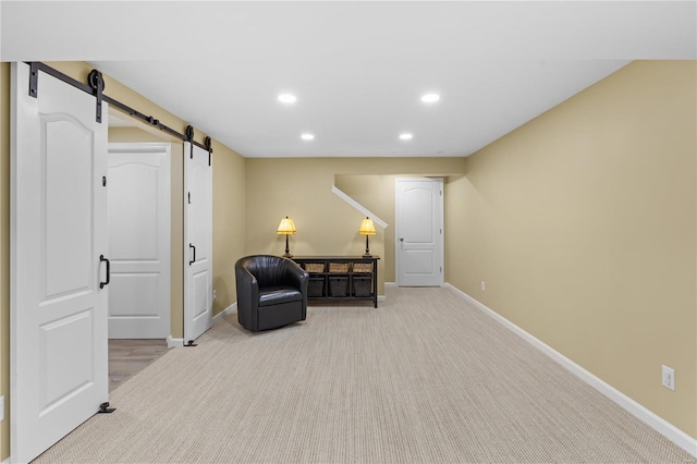 living area featuring light colored carpet and a barn door