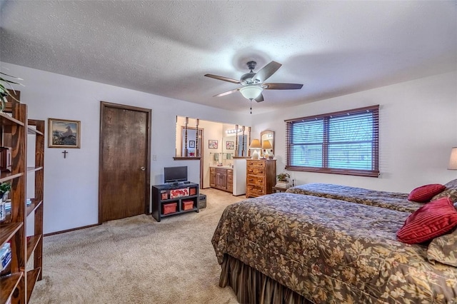 bedroom with ceiling fan, light colored carpet, a textured ceiling, and ensuite bath