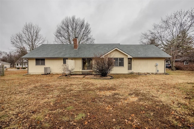 rear view of property featuring central AC unit and a yard