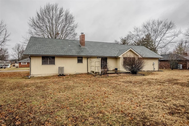 rear view of property with central AC unit and a lawn