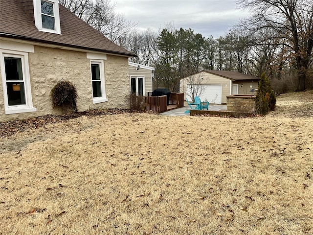 view of yard with an outbuilding, a garage, and a patio