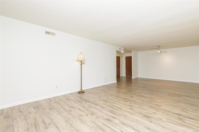 unfurnished room with light wood-type flooring, visible vents, and baseboards