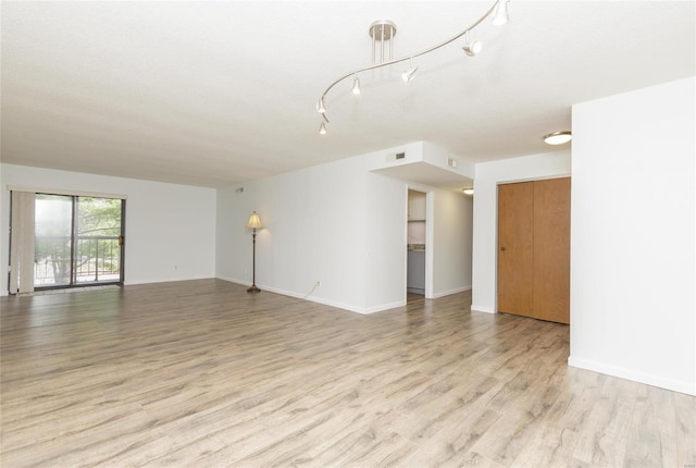 unfurnished living room with light wood finished floors, visible vents, and baseboards