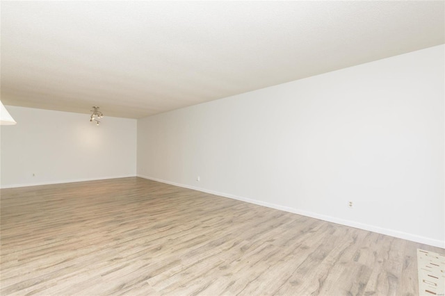 empty room with light wood-type flooring and baseboards