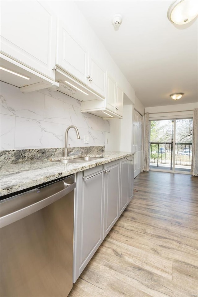 kitchen with dishwasher, decorative backsplash, light wood-style flooring, white cabinetry, and a sink