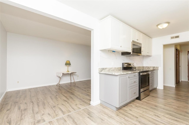 kitchen with visible vents, white cabinetry, stainless steel appliances, light wood finished floors, and baseboards