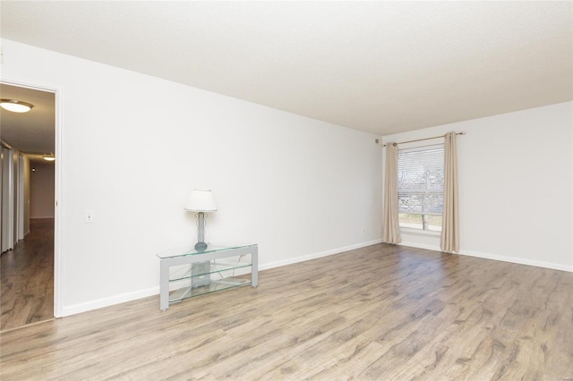 spare room with wood finished floors and baseboards