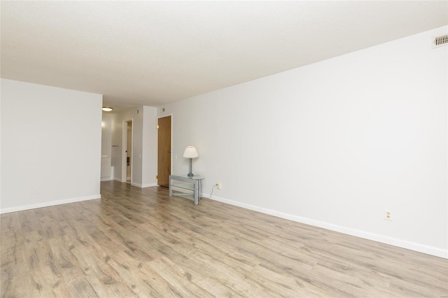 spare room featuring visible vents, baseboards, and light wood finished floors