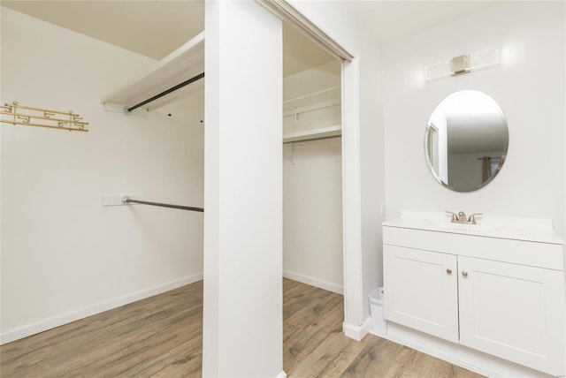 bathroom with vanity, wood finished floors, and baseboards