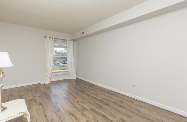 unfurnished room with visible vents, baseboards, and wood finished floors