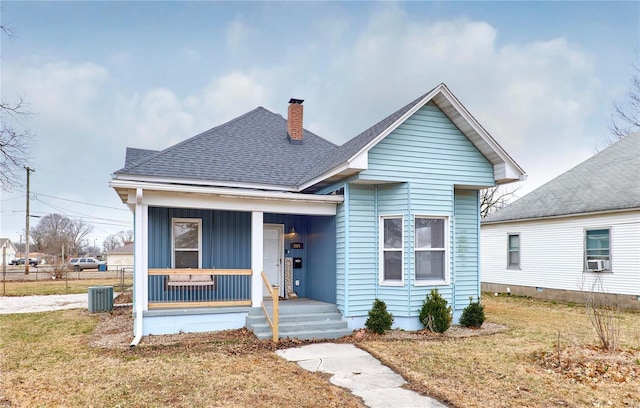 bungalow-style home with a porch, cooling unit, and a front lawn