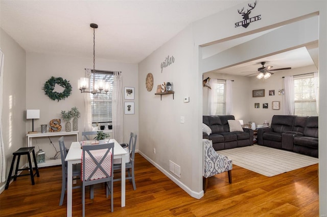 dining space featuring hardwood / wood-style flooring and ceiling fan with notable chandelier