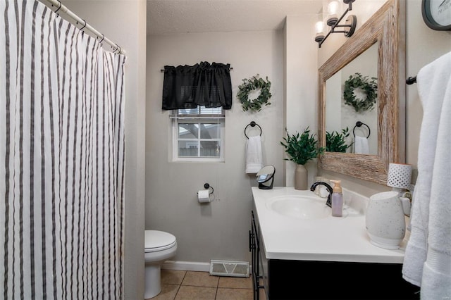 bathroom featuring tile patterned flooring, vanity, a textured ceiling, and toilet