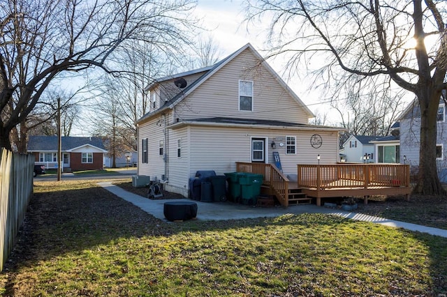 rear view of property featuring a wooden deck and a lawn