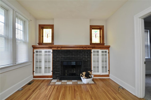 unfurnished living room with a brick fireplace, a healthy amount of sunlight, and light hardwood / wood-style floors