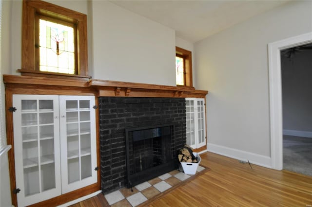 unfurnished living room featuring hardwood / wood-style flooring and a brick fireplace