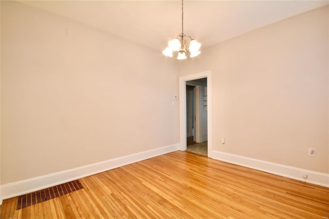 unfurnished room with wood-type flooring and an inviting chandelier