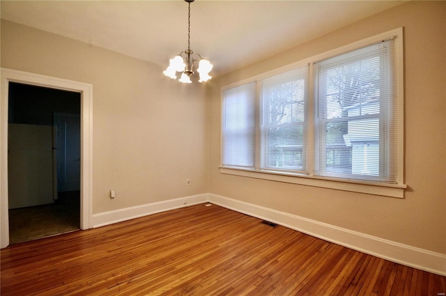 spare room with hardwood / wood-style floors and a chandelier