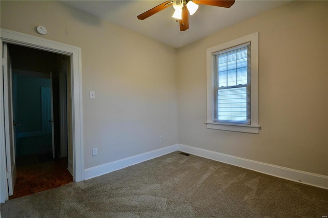 empty room featuring dark carpet and ceiling fan