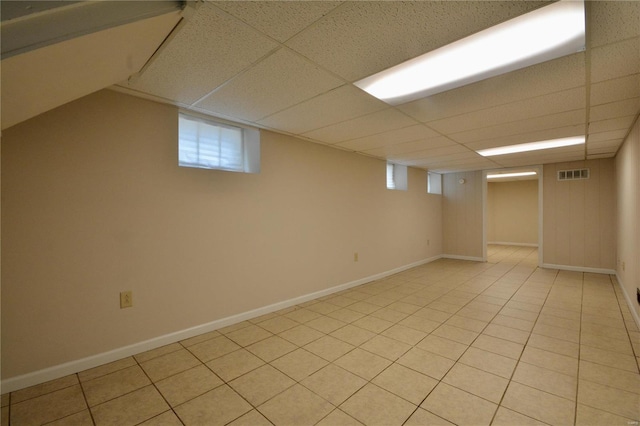 basement featuring light tile patterned flooring and a drop ceiling