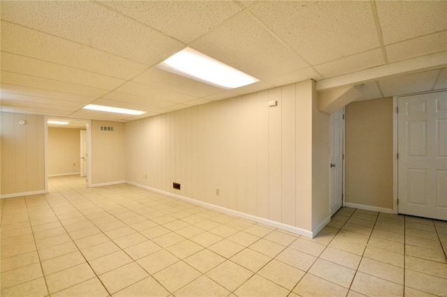 basement featuring light tile patterned floors and a paneled ceiling