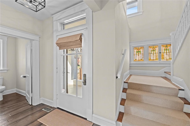 entryway featuring dark wood-style floors, baseboards, stairs, and visible vents