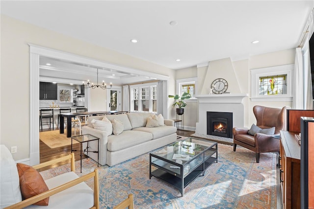 living area with a large fireplace, a notable chandelier, wood finished floors, and recessed lighting