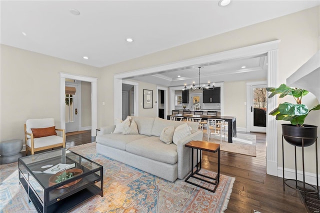 living room featuring a tray ceiling, dark wood-style flooring, recessed lighting, a chandelier, and baseboards