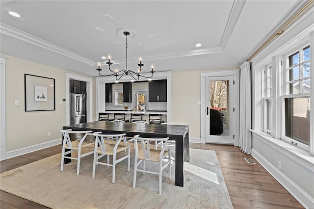 dining area featuring visible vents, ornamental molding, wood finished floors, a chandelier, and baseboards