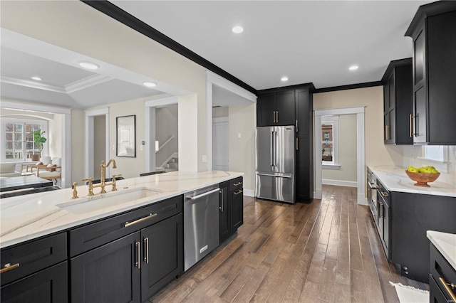 kitchen featuring dark wood finished floors, crown molding, stainless steel appliances, a sink, and dark cabinets