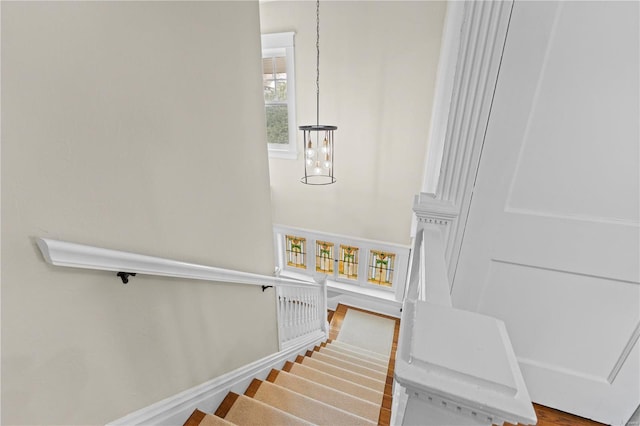 stairway featuring an inviting chandelier, baseboards, and wood finished floors