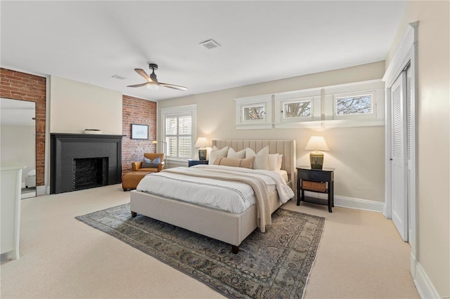 bedroom with light carpet, visible vents, baseboards, a closet, and a brick fireplace