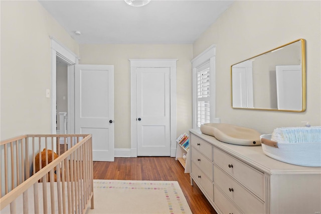 unfurnished bedroom featuring a nursery area, light wood finished floors, and baseboards