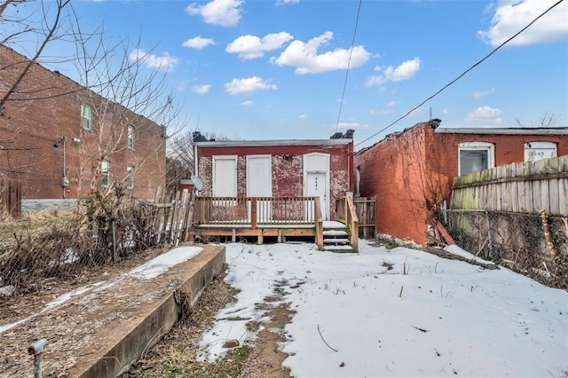 snow covered back of property featuring a deck