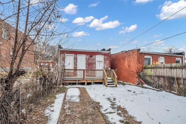 snow covered house featuring a wooden deck