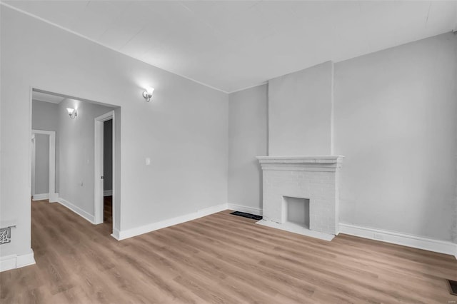 unfurnished living room featuring a fireplace and light hardwood / wood-style floors