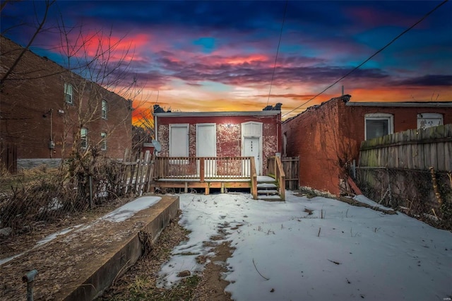 snow covered rear of property with a wooden deck