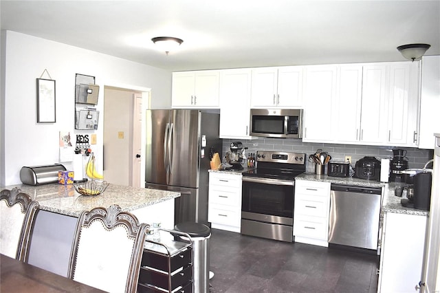 kitchen featuring stainless steel appliances, backsplash, white cabinets, and light stone counters